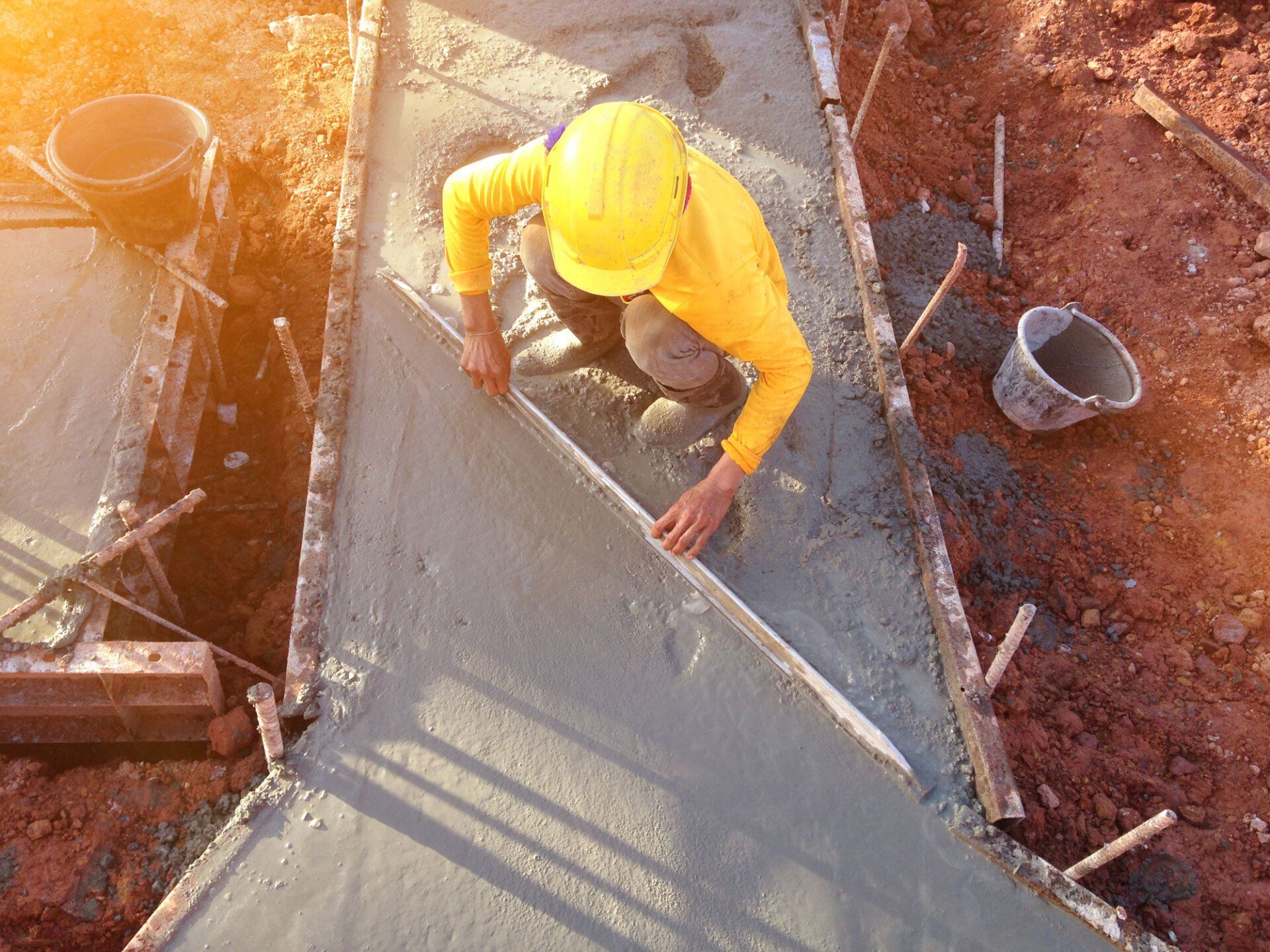 man hand spreading concrete mix with trowel in foundation