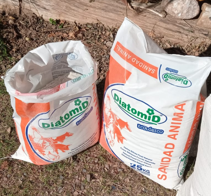 Dos bolsas blancas y naranjas de producto zoosanitario “DiatomiD” de 25 kg cada una.
