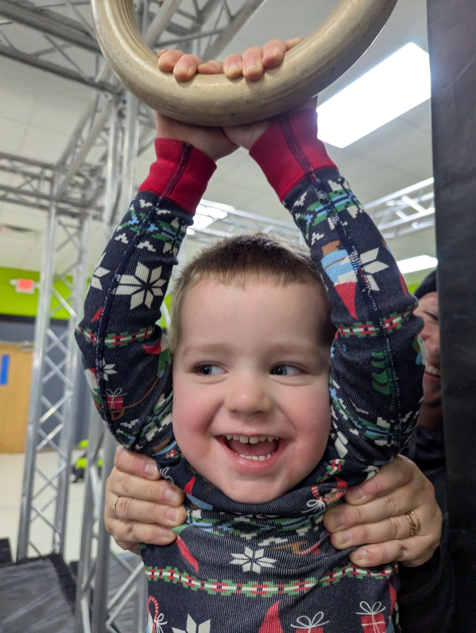 A young boy wearing a helmet is walking across a ropes course
