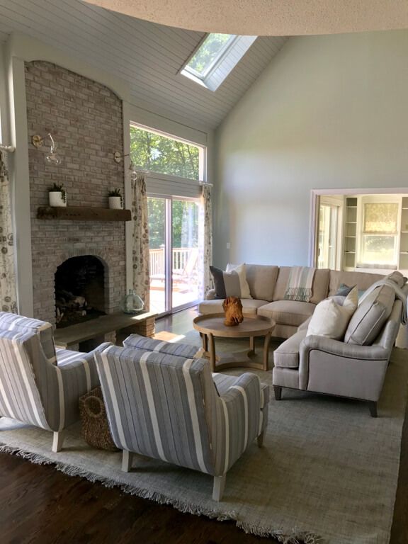 Living room with a brick fireplace, skylight, and neutral-colored furniture.