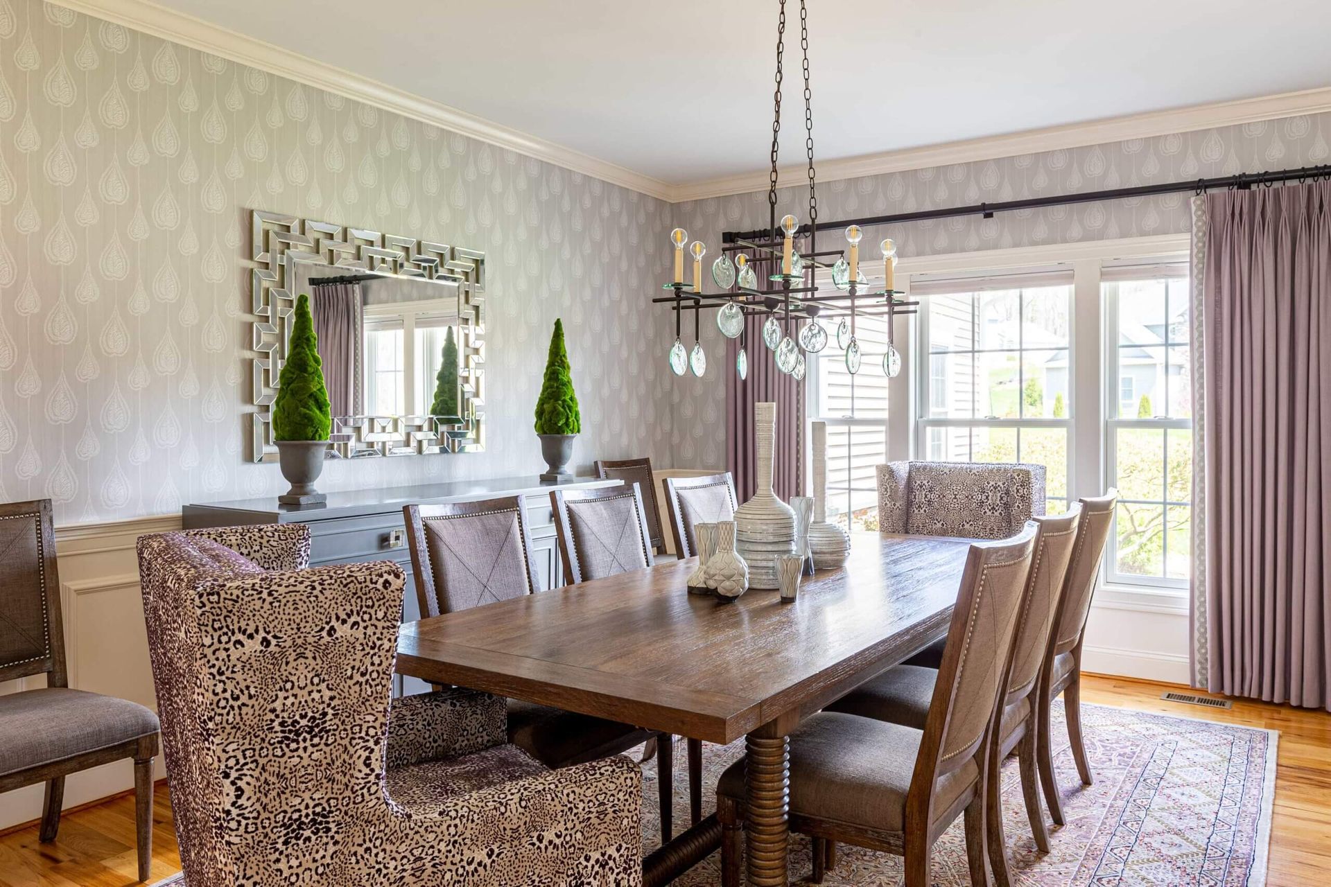 Formal dining room with a long wooden table, patterned chairs, and a large mirror.