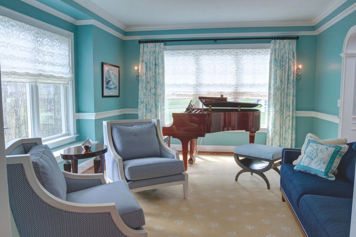 A living room with a grand piano, blue walls and accents, and light-colored furniture.
