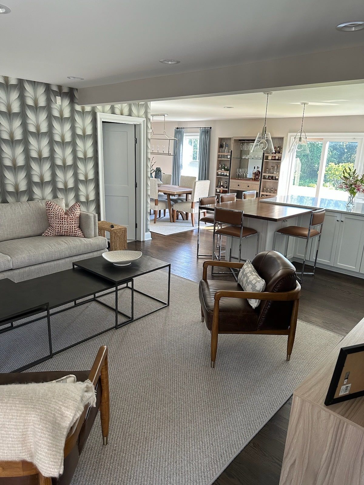 Living room with butterfly wallpaper, open to dining area and kitchen. Furniture includes a sofa, chair, and coffee table.