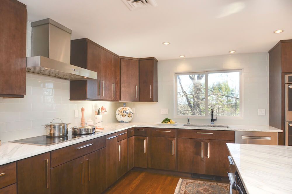 Modern kitchen with dark wood cabinets, white countertops, and stainless steel appliances.