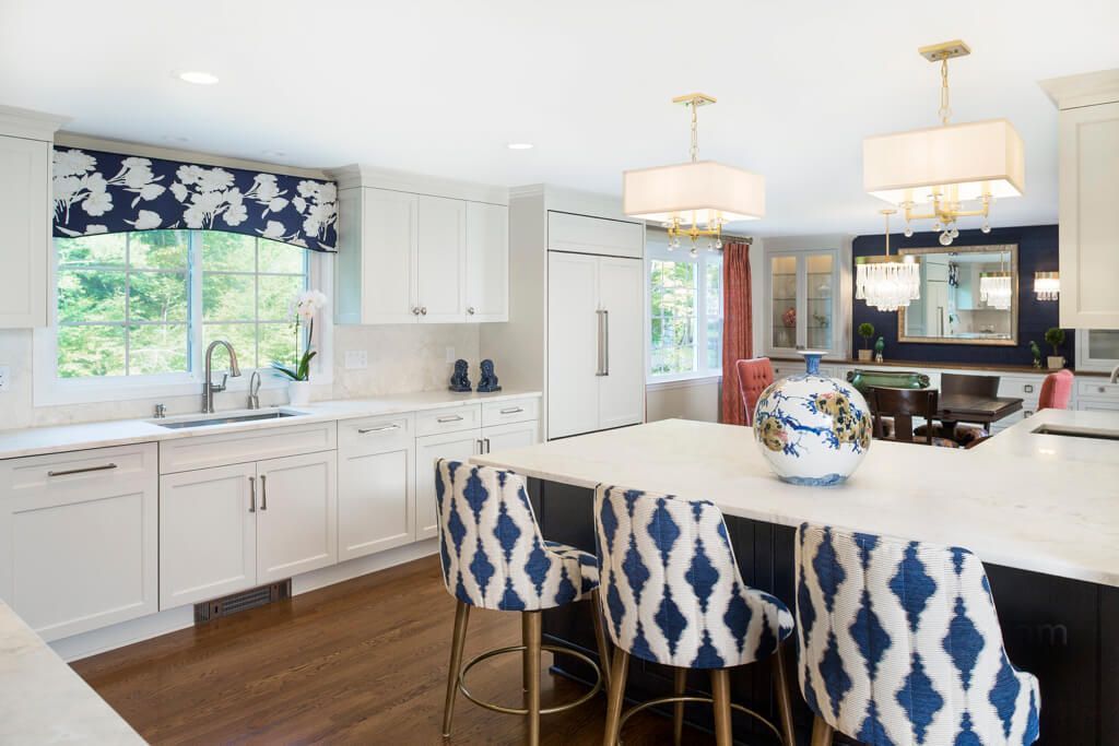 Kitchen with white cabinets, blue and white patterned stools, and a large island.