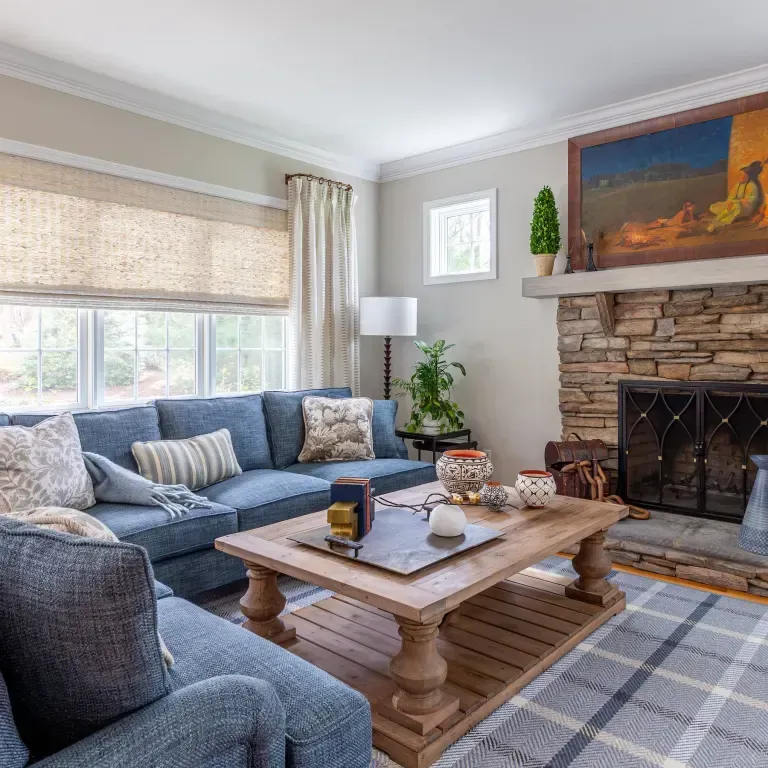 Living room with blue sectional, stone fireplace, and plaid rug.