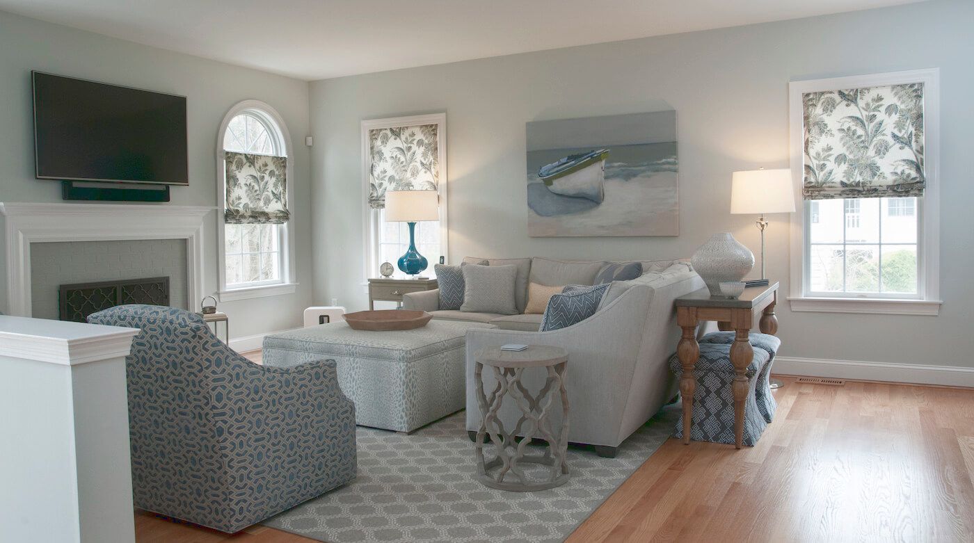Living room with blue and white decor, fireplace, and artwork of a boat on the beach.