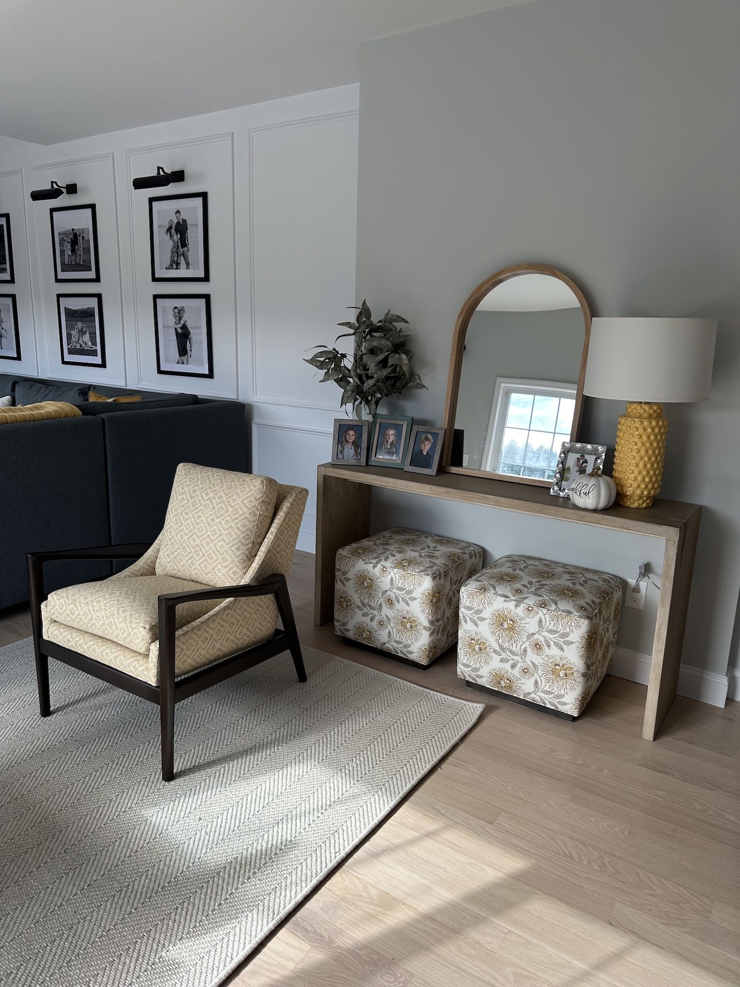 Living room with a patterned armchair, console table with a mirror, and patterned ottomans.