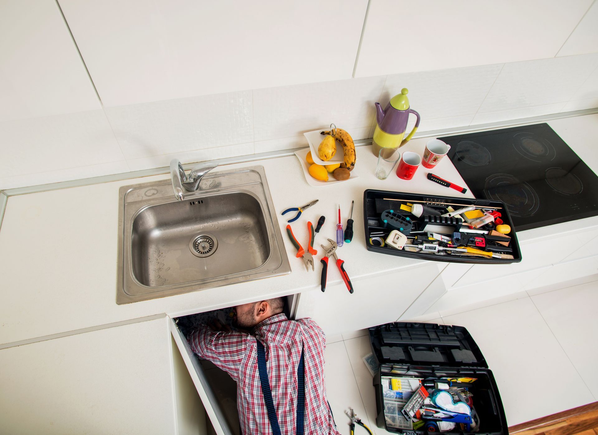 An emergency plumber performing kitchen sink pipe repair.