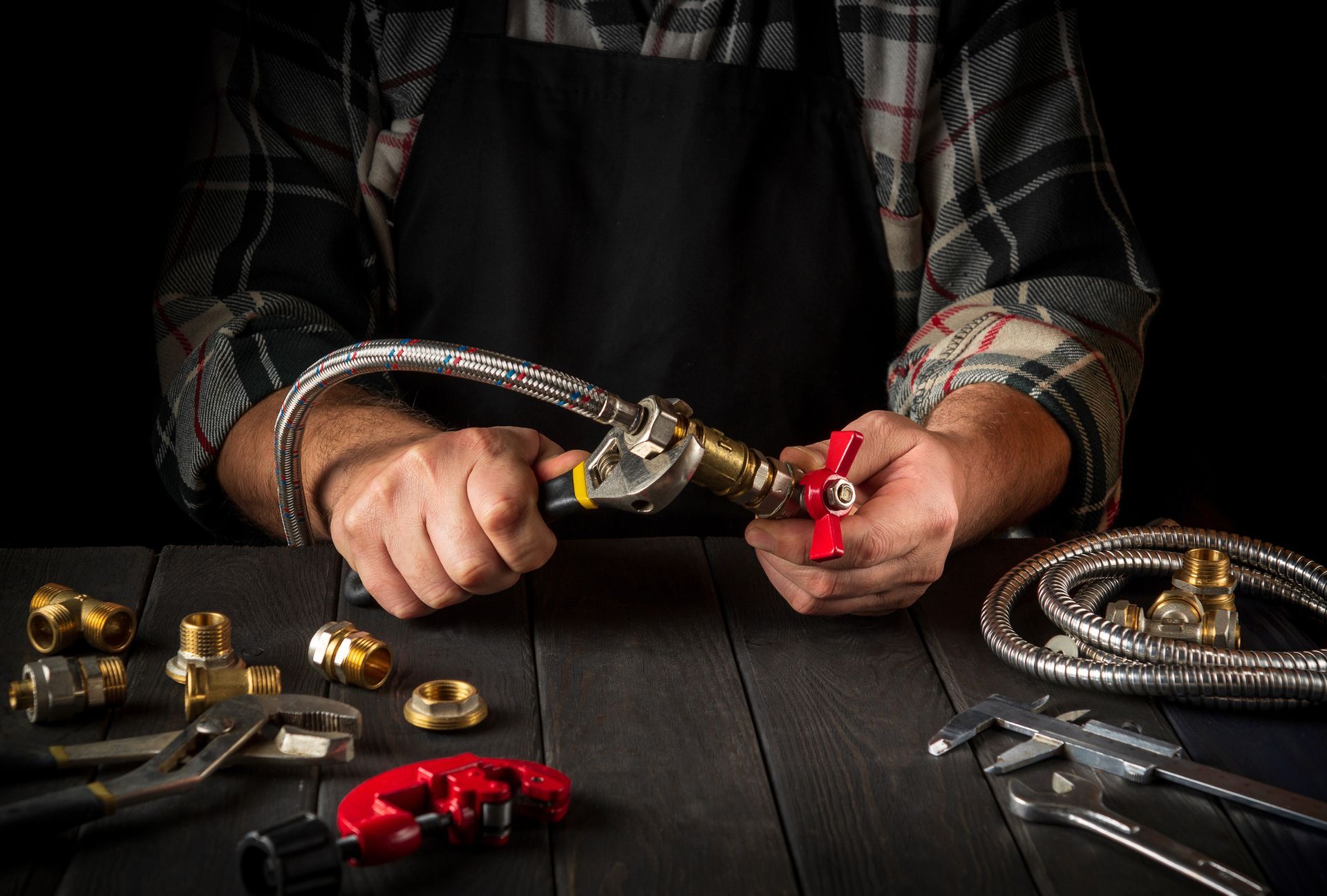 Skilled plumber connects high-pressure hose to faucet using wrench during plumbing service.