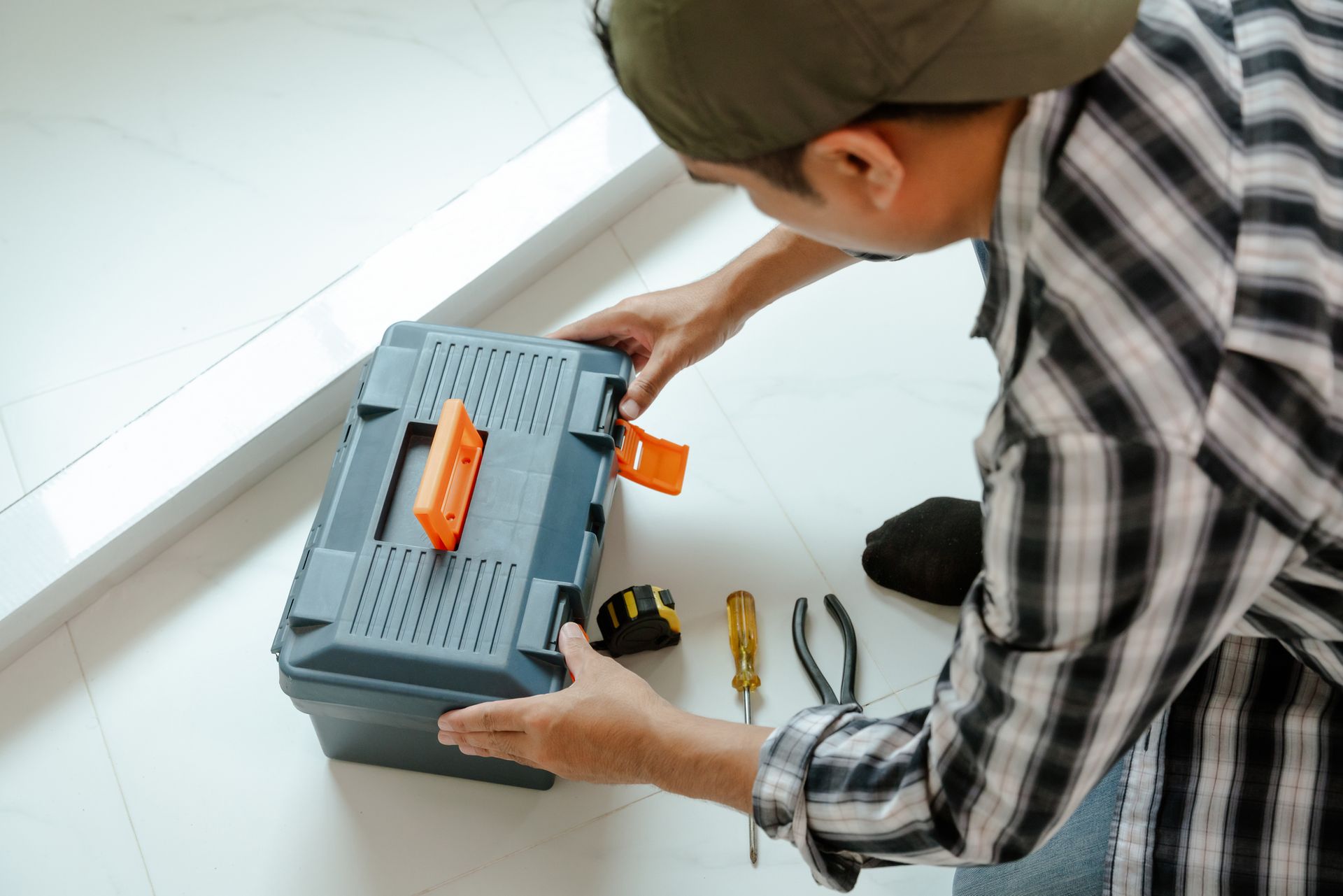 Person opening a toolbox with tools scattered on the floor.