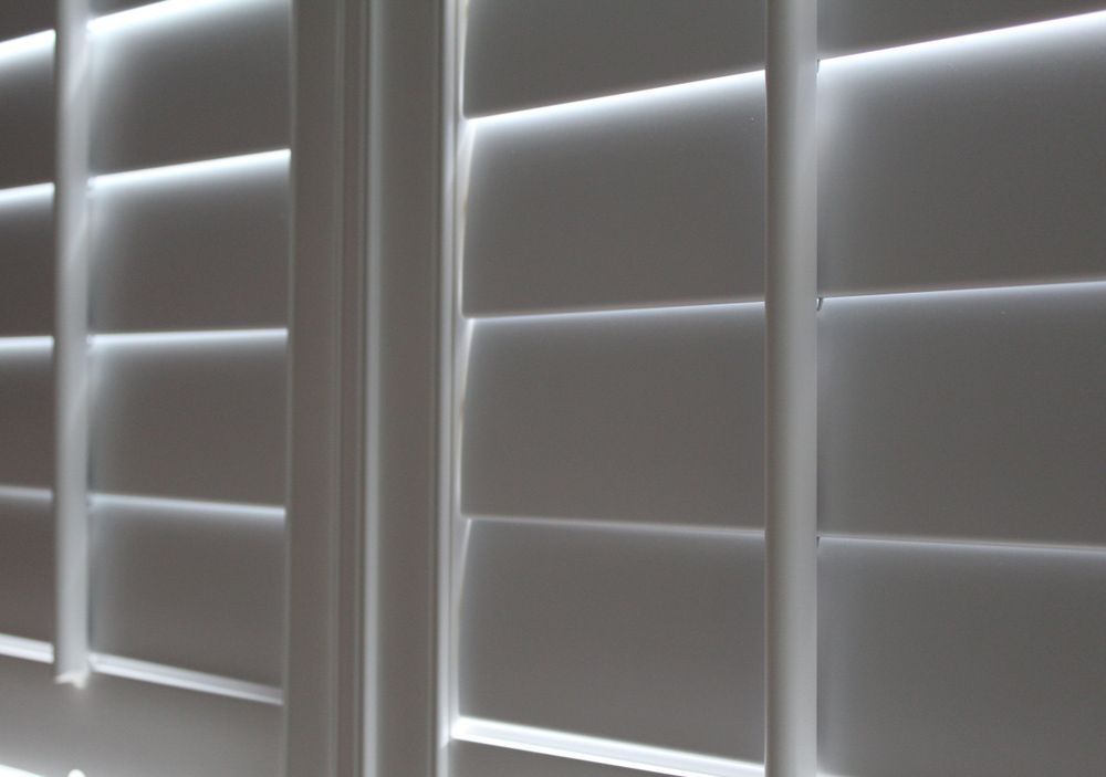 A Close Up Of Three White Shutters On A Window — Gaeta's Upholstery Blinds & Awnings in Grafton, NSW
