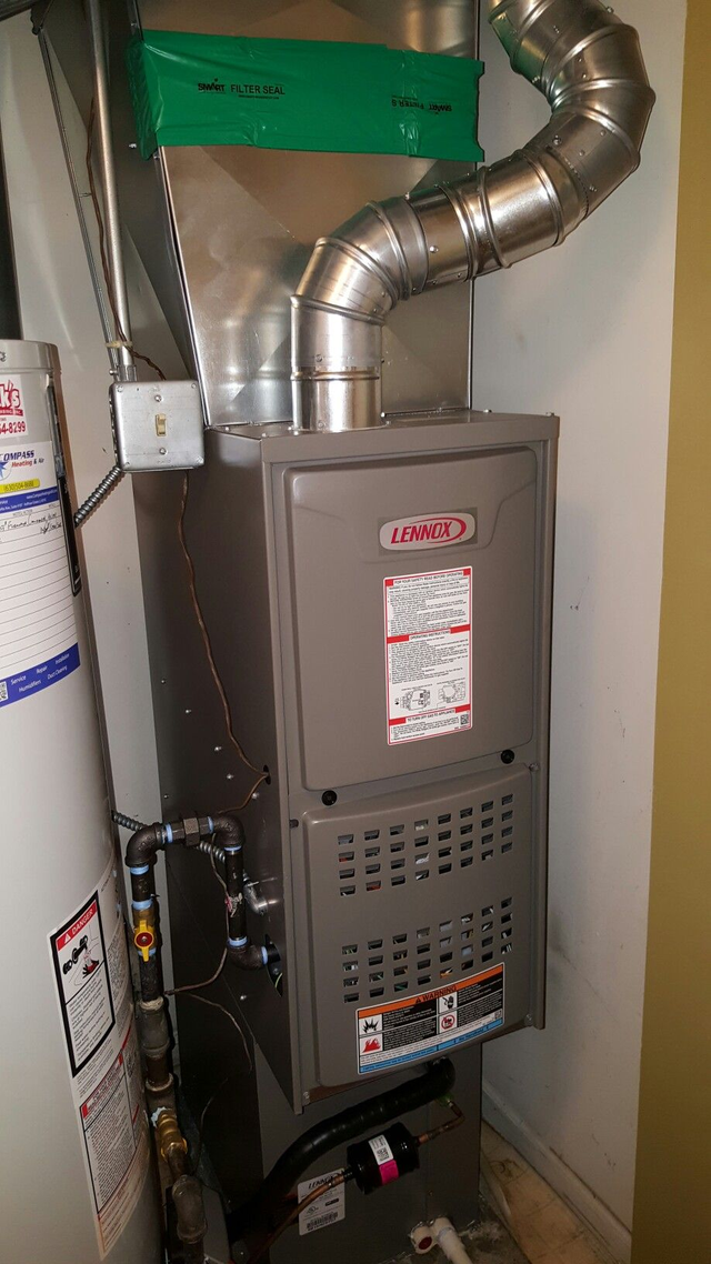 A Lennox furnace, silver ductwork, and water heater in a utility room.