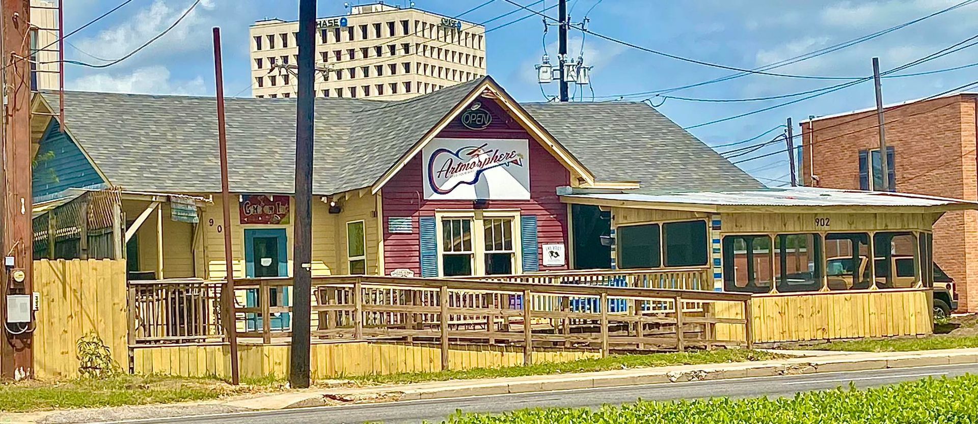 A one-story building with a deck, painted yellow and red, with a sign that says