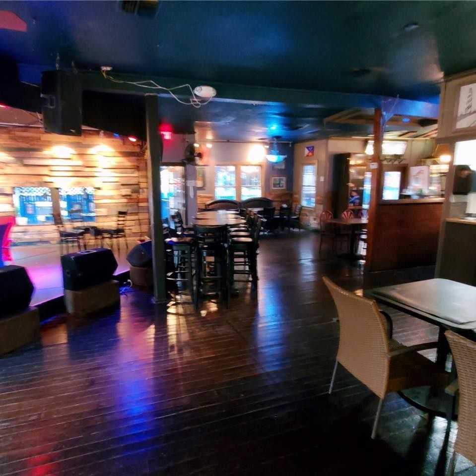 Empty bar with dark wood floors and tables. Stage left with wooden wall.