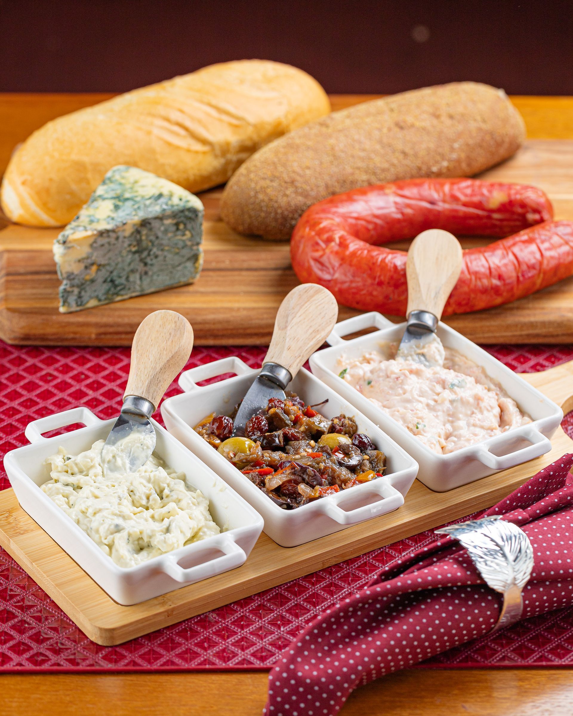 Uma tábua de corte de madeira com três tigelas de comida sobre ela.