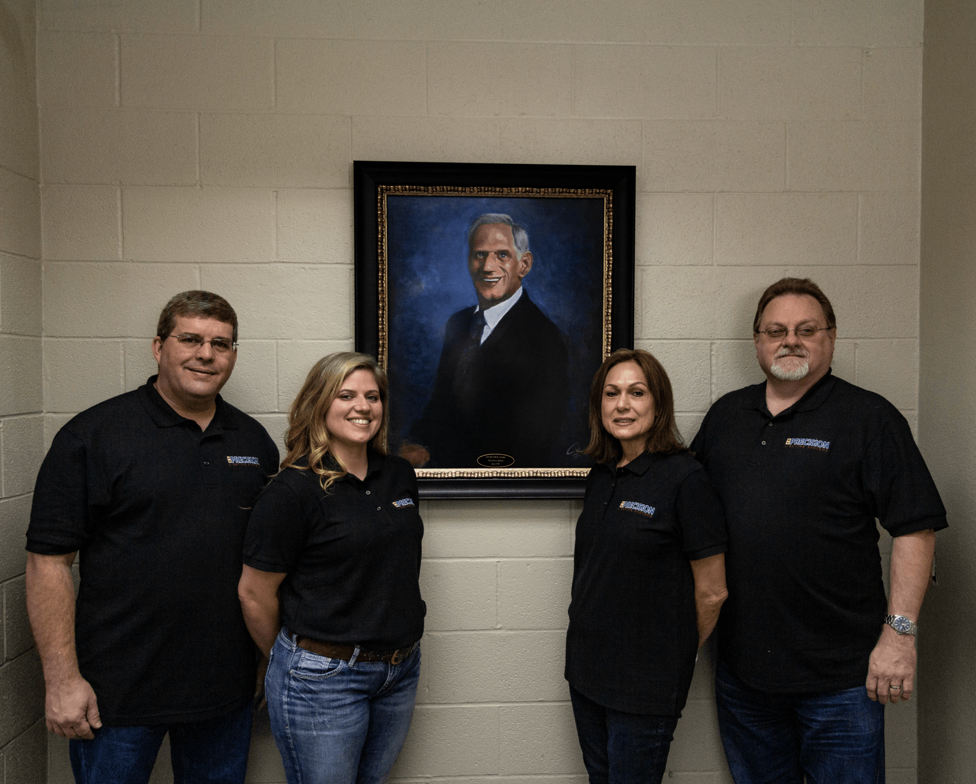 current board of directors standing in front of portrait of jay blumer at Precision Lighting Systems in Hot Springs, AR