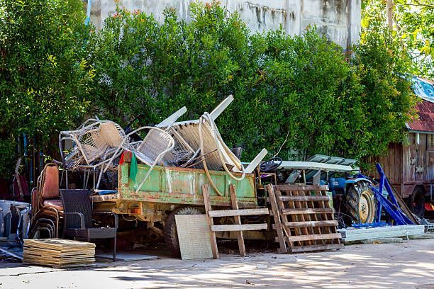 A green truck filled with furniture and pallets in a yard.