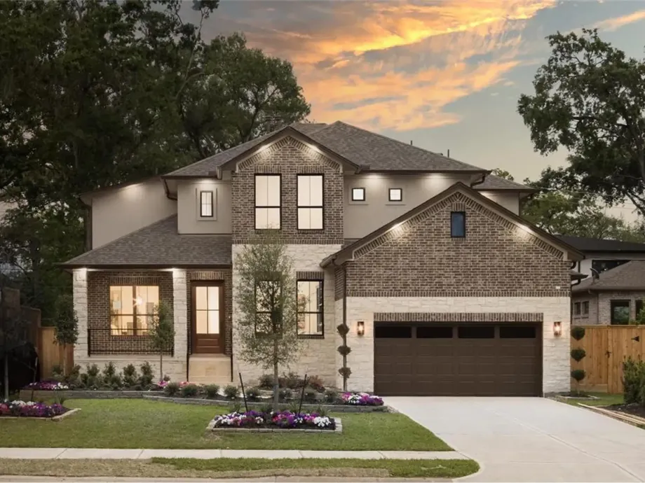A large house with a large garage and a sunset in the background.