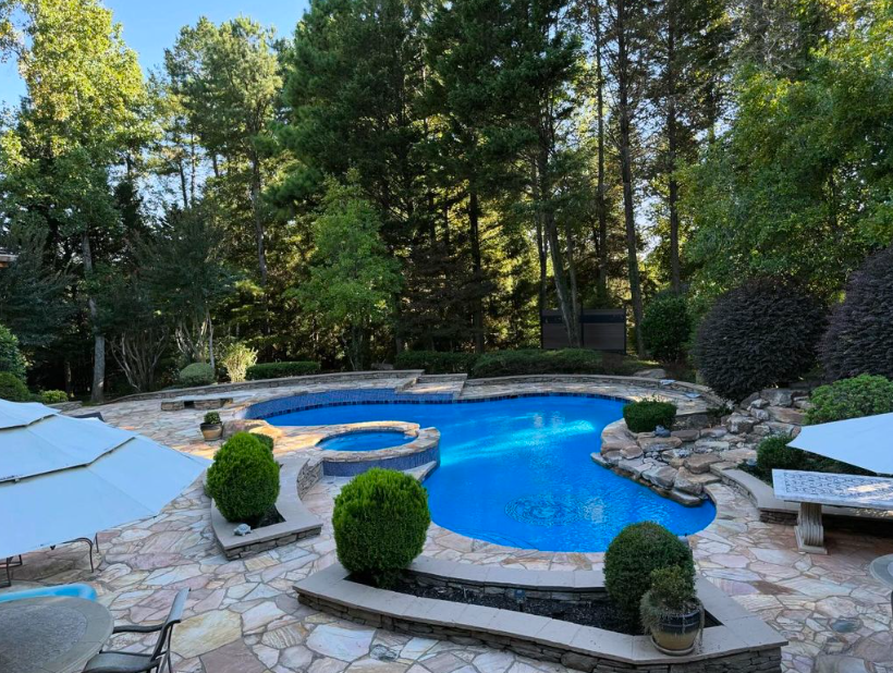 A large swimming pool in a backyard surrounded by trees