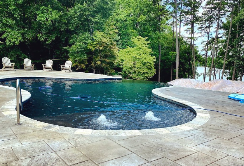 A large swimming pool is surrounded by trees and chairs.