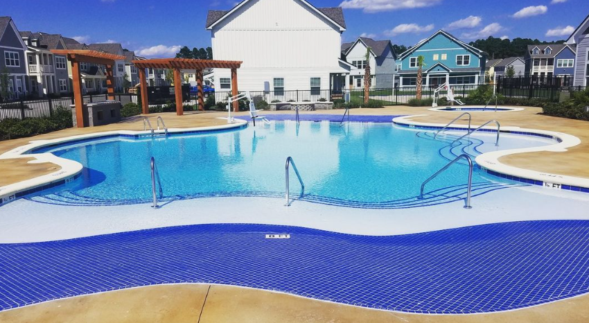 There is a large swimming pool in the middle of a residential area.