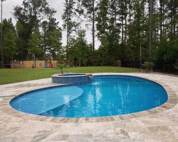 A large swimming pool surrounded by trees in a backyard.