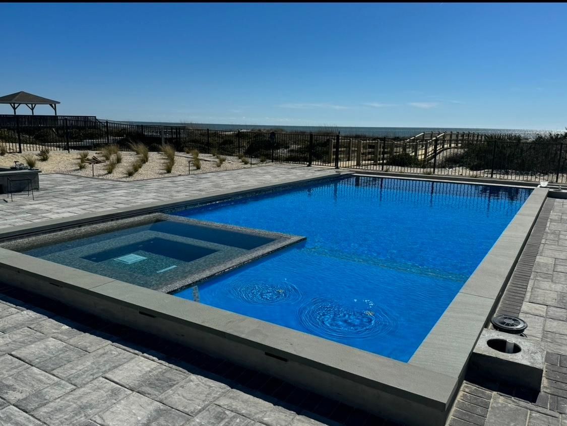 A large swimming pool with a hot tub in the middle and a gazebo in the background.