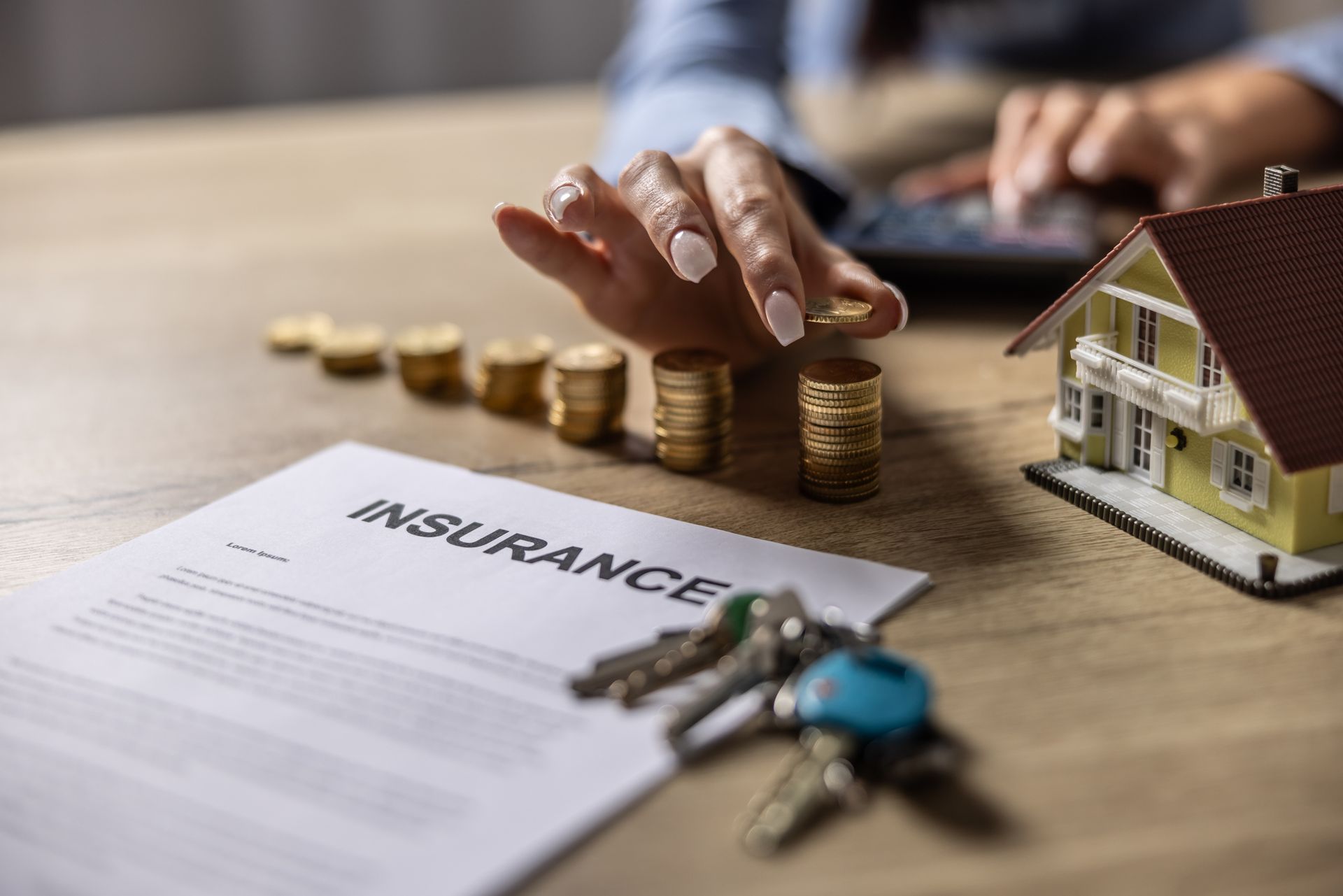 A public adjuster is counting coins. An insurance form, keys, and a model home are also on the table
