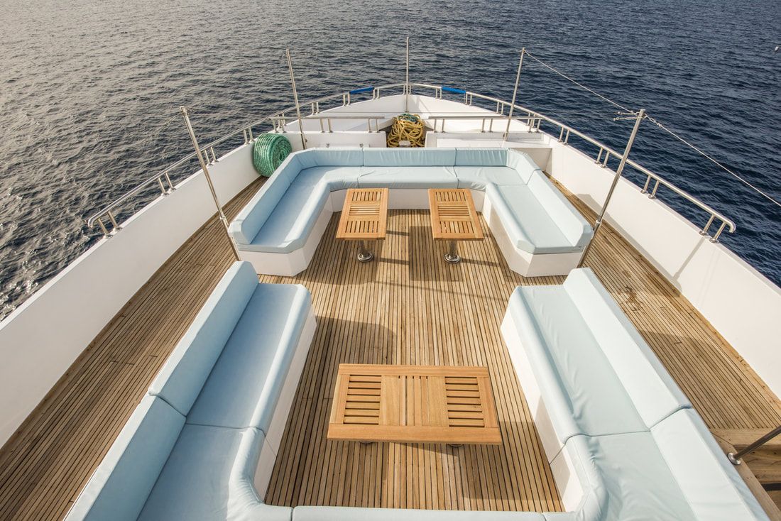 Ship bow layered in teak decking with couches and tables for dining