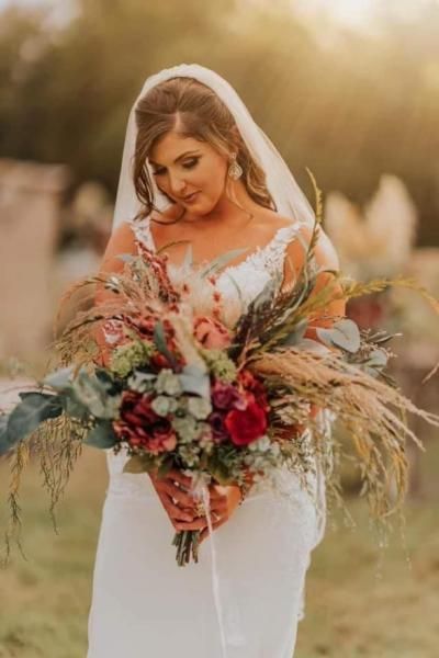 Bridal portrait of a woman in a white dress holding a large bouquet outdoors