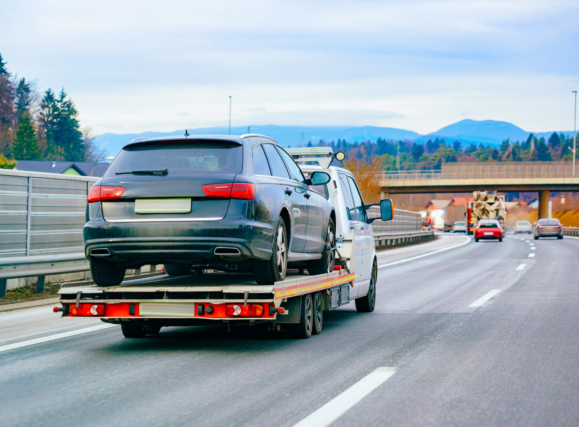 A tow truck is towing a car on a highway.