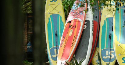 A row of surfboards are stacked on top of each other.