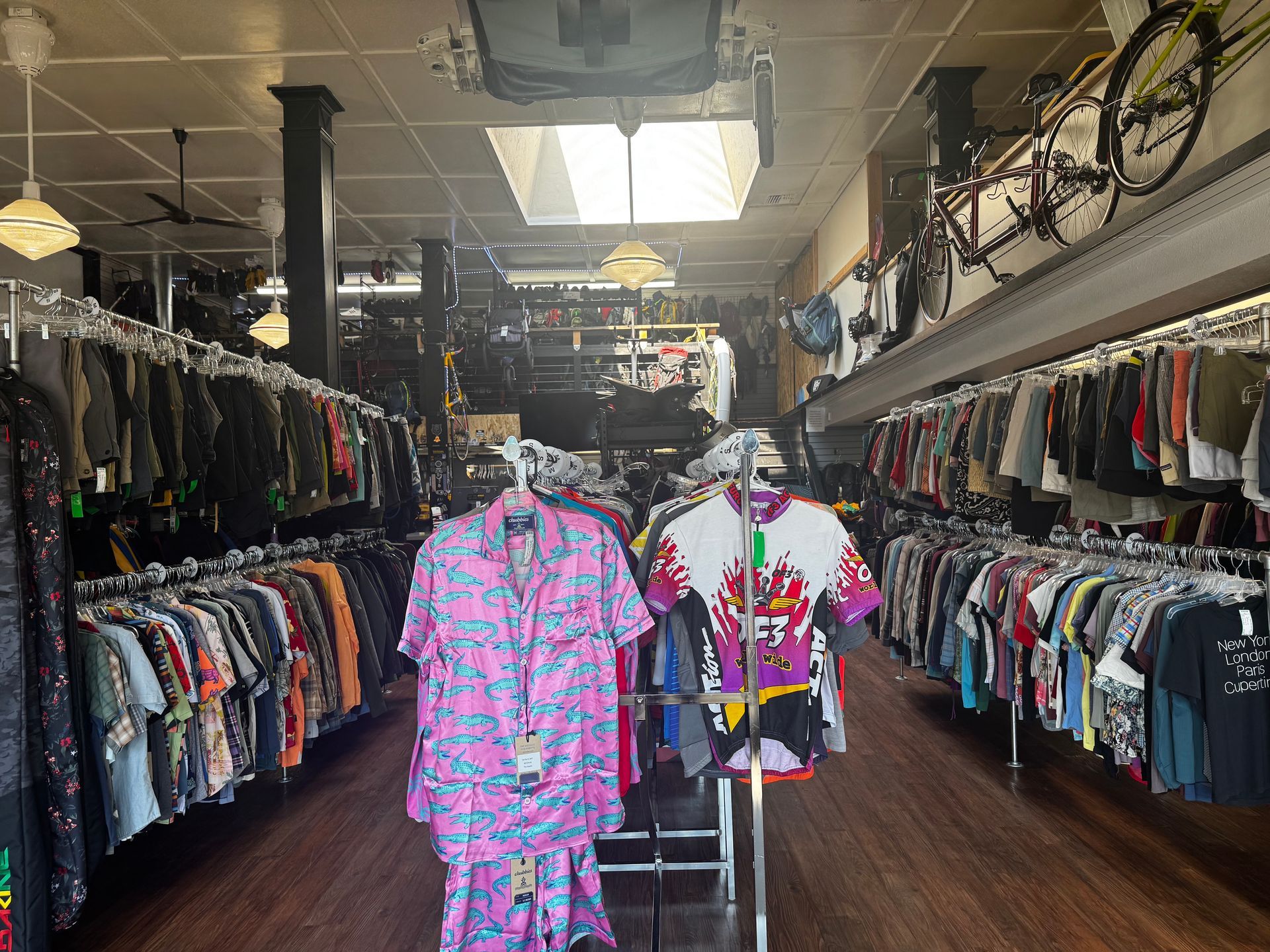 A store filled with lots of clothes and a bicycle on the wall.