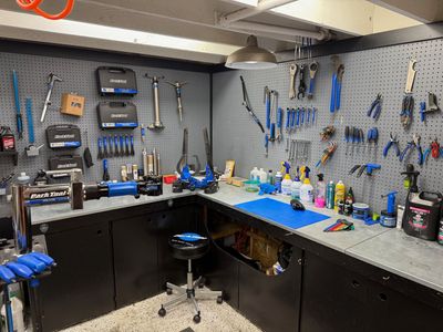 A workbench filled with lots of tools and a stool in a garage.