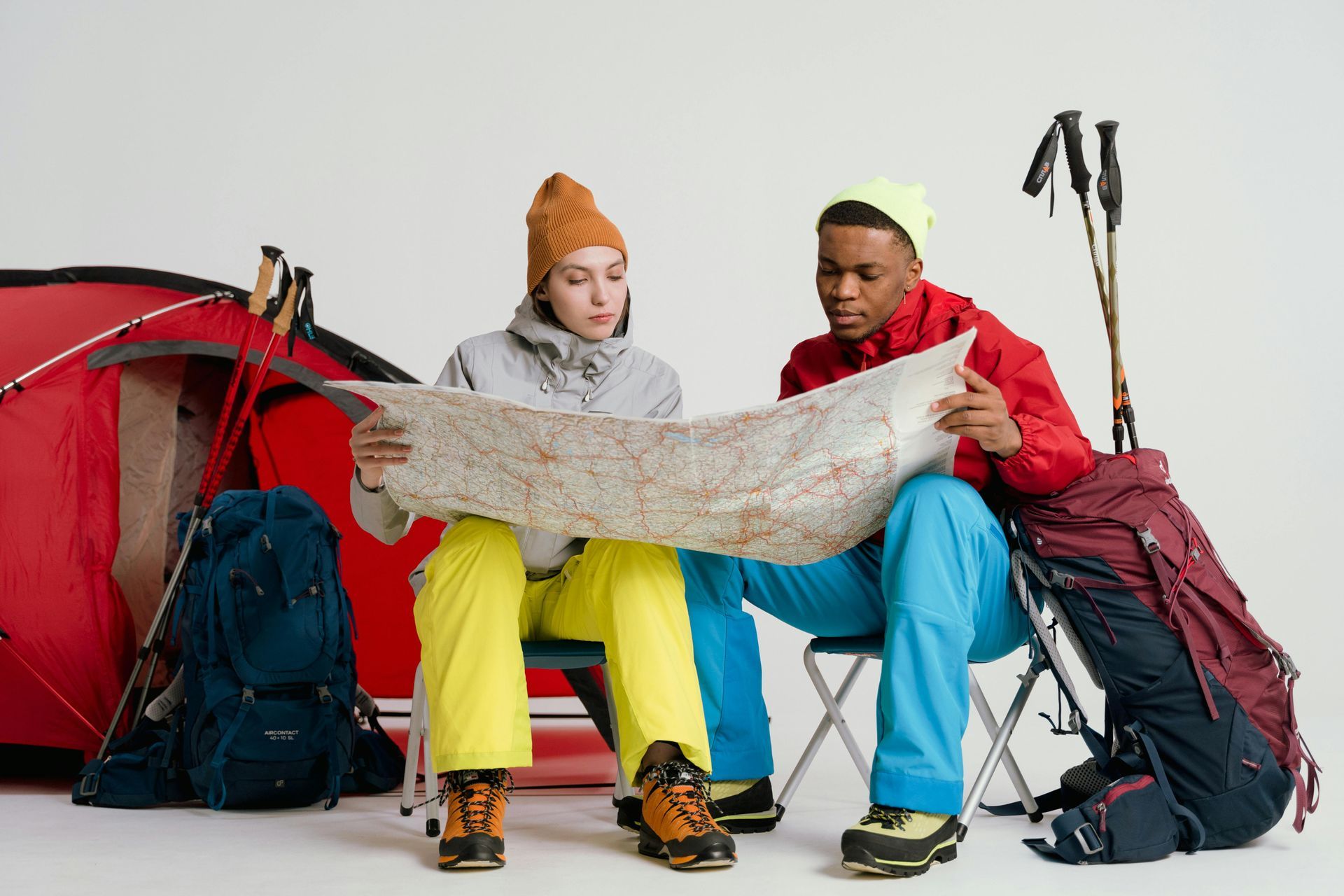 Hikers wearing hiking gear, holding a map and with hiking bag beside them