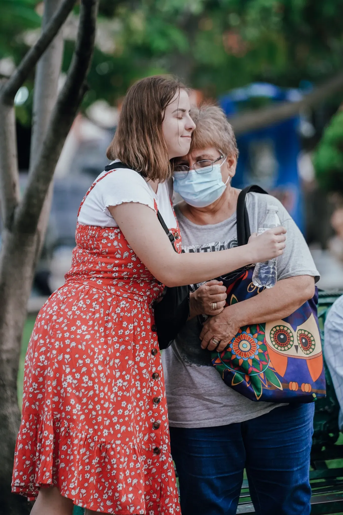 A young woman is hugging an older woman wearing a mask.