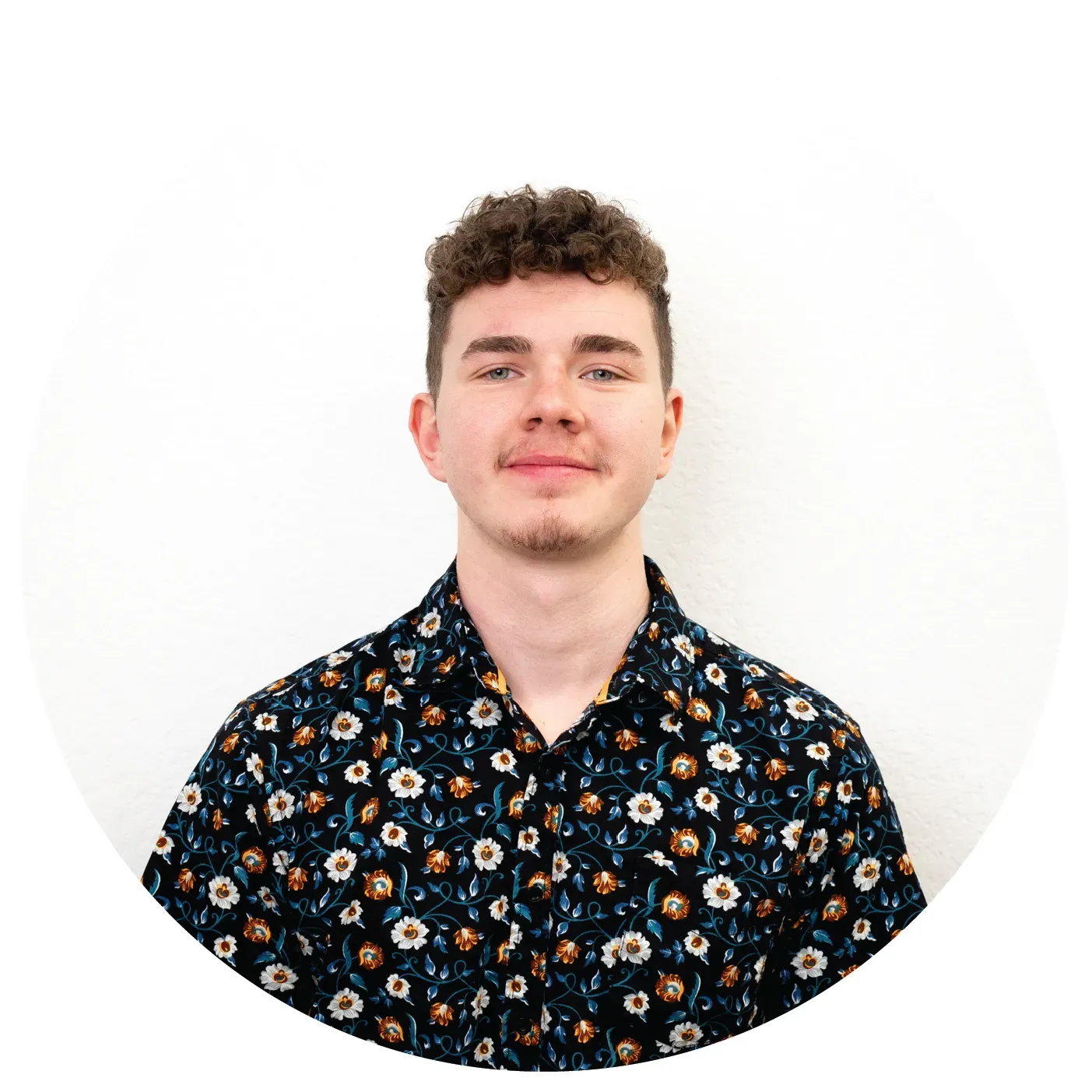 A bald man with a beard is wearing a white shirt and smiling.