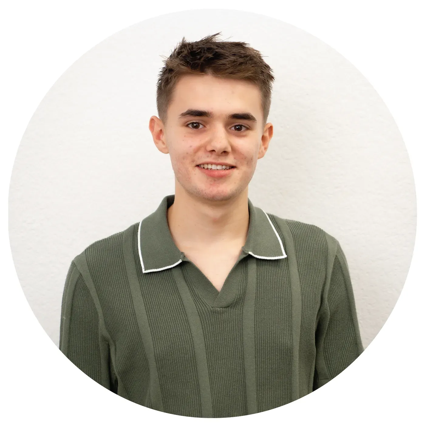A man in a brown polo shirt is smiling in front of a tree.