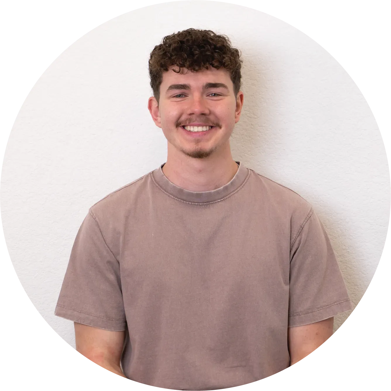 A bald man with a beard is wearing a white shirt and smiling.