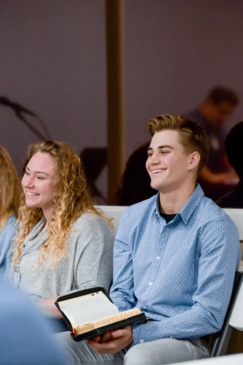 A man and a woman are sitting in chairs holding a bible.