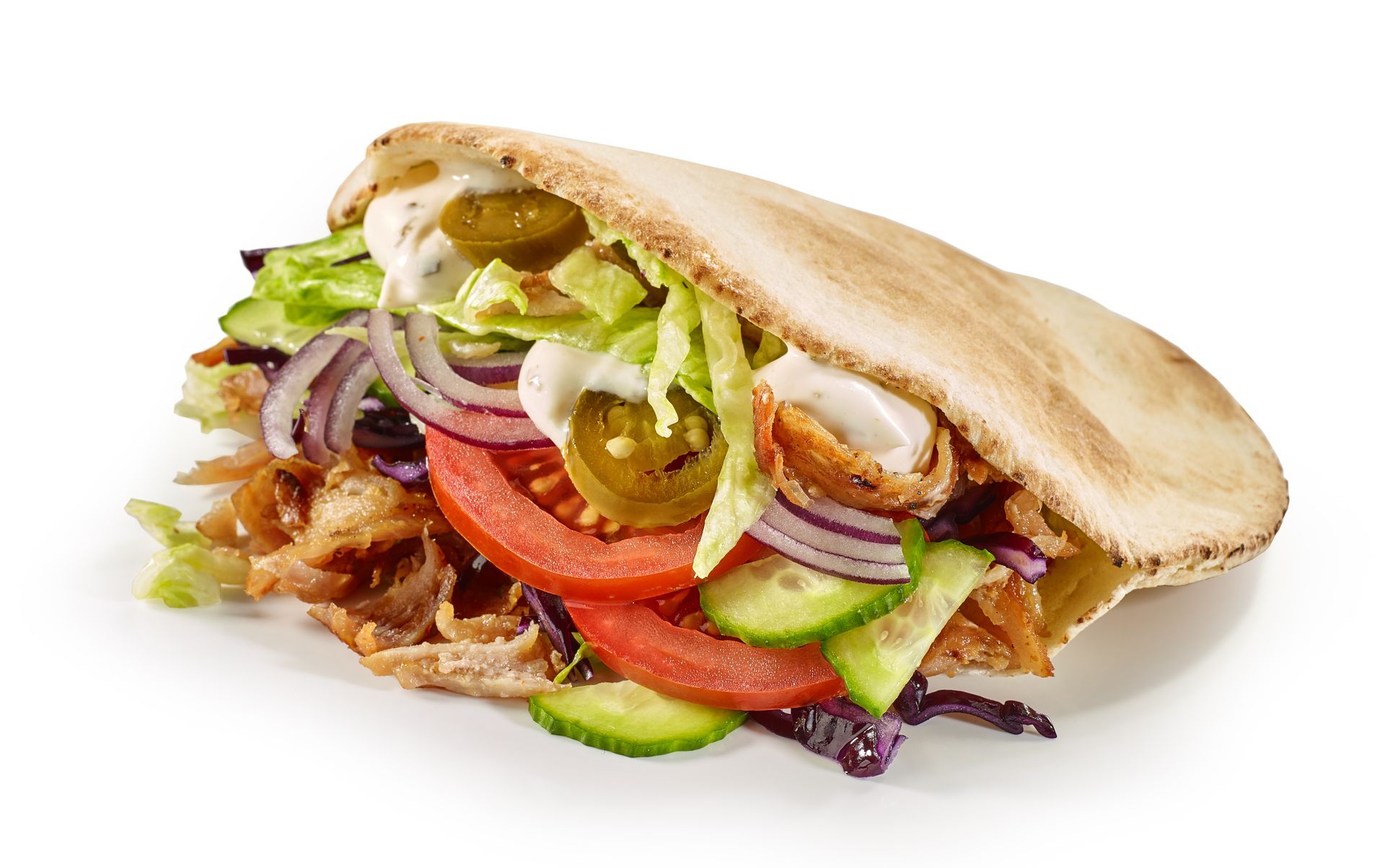 A pita sandwich with chicken , lettuce , tomatoes , onions and jalapenos on a white background.