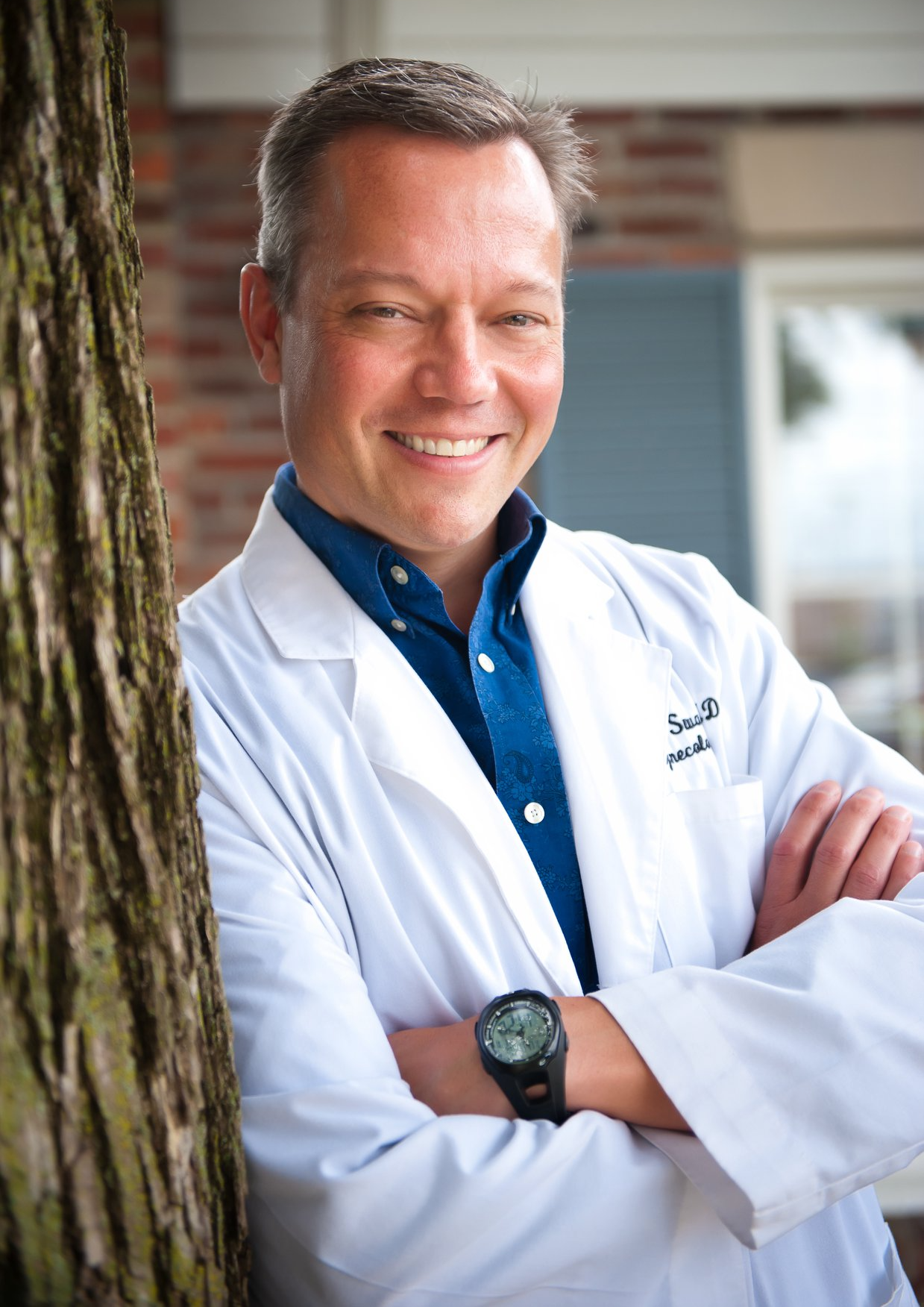 Dr. Michael Swan in lab coat leaning against a tree