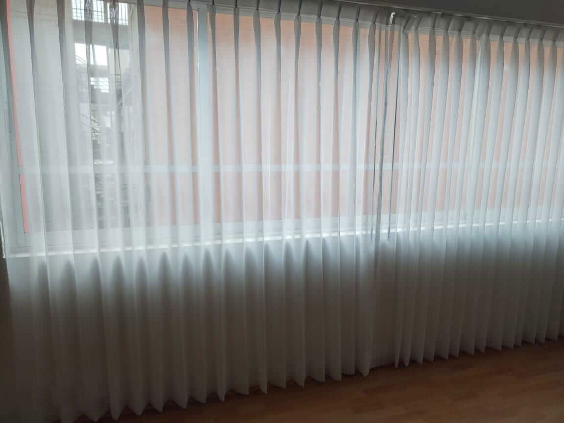 Una habitación con una ventana grande y cortinas blancas.
