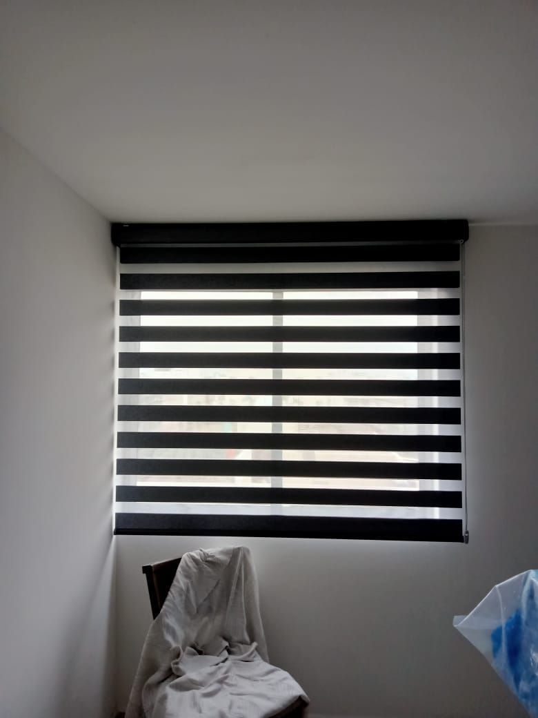 Una habitación con una silla y una ventana con persianas.