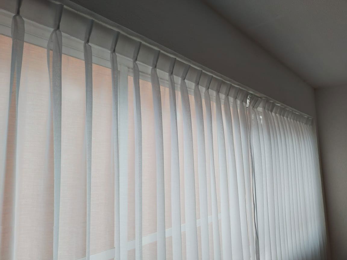 Una cortina blanca cuelga de una ventana de una habitación.