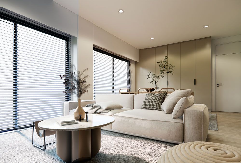 Una sala de estar con un sofá blanco, una mesa de café y grandes ventanales.