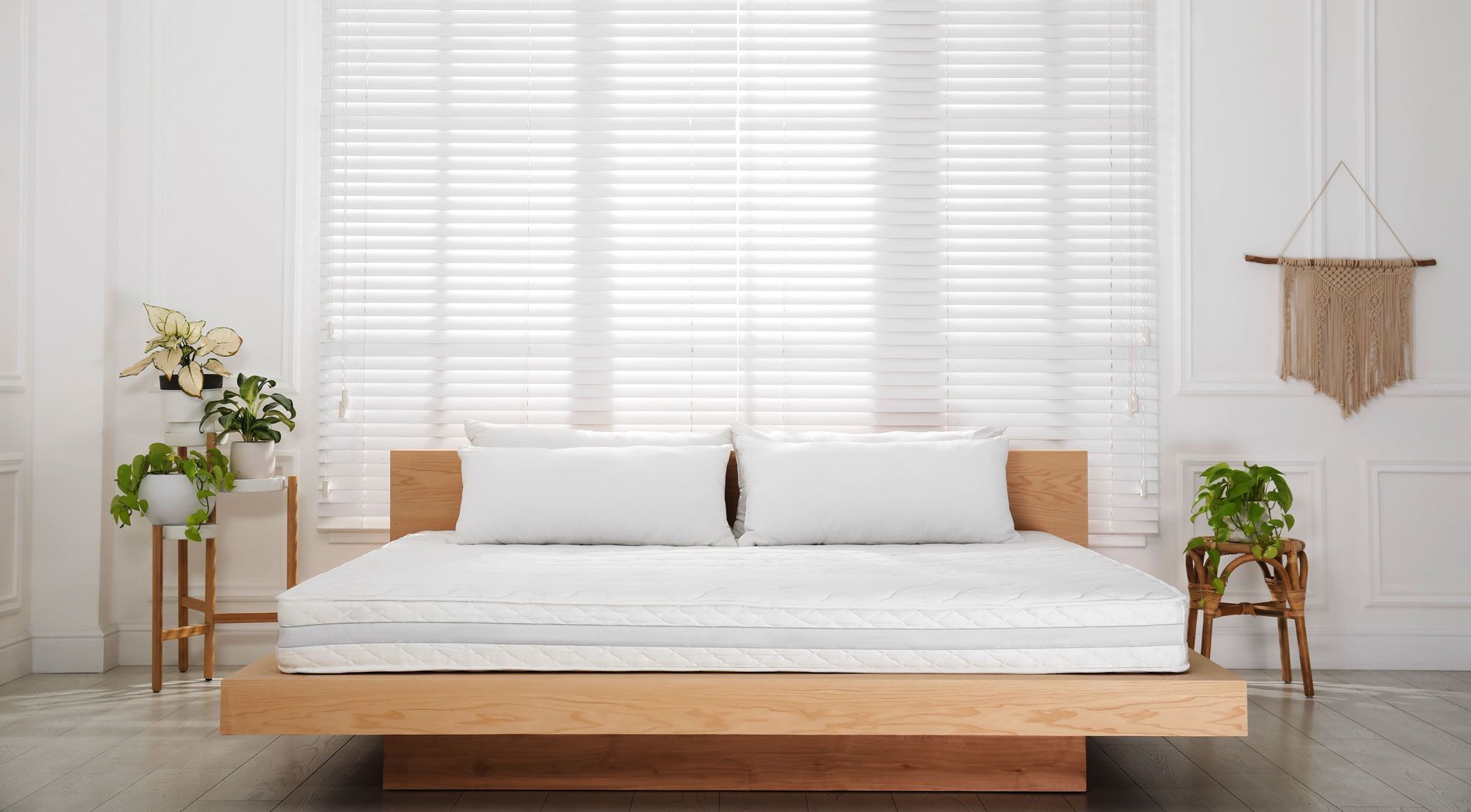 Una cama con estructura de madera y sábanas blancas en un dormitorio.