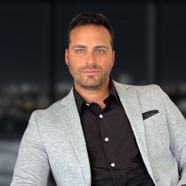 A man wearing a grey jacket and a black dress shirt.