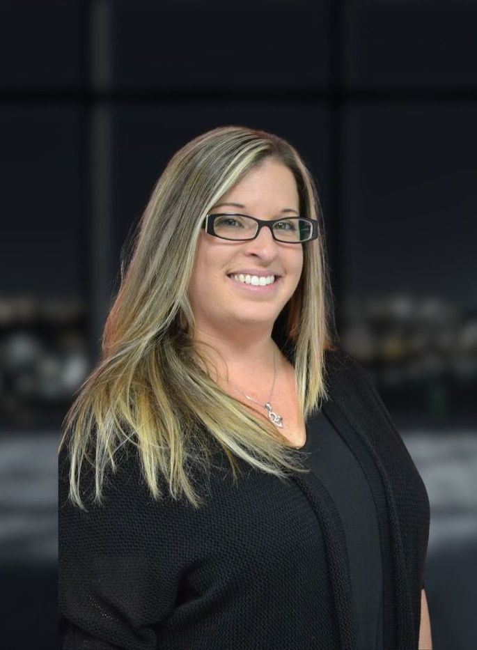 A woman wearing glasses and a black shirt is smiling for the camera.